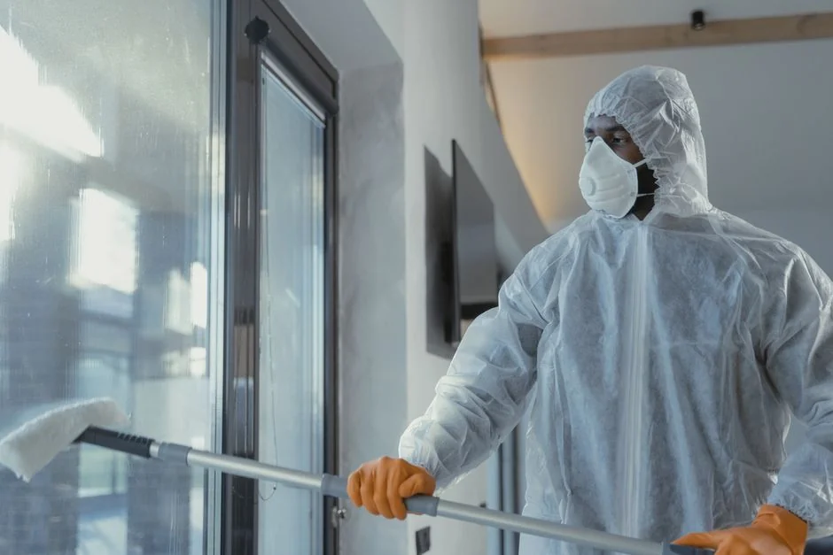 Un laveur de vitres masculin nettoyant, en journée, la toiture vitrée extérieure depuis le dessus à l’aide d’un outil.